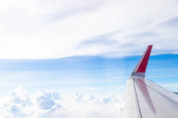 Plane wings in the sky with fluffy white clouds nature background