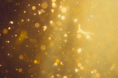 Siyah arkaplanda koyu soyut altın bokeh parıltısı