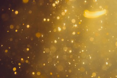 Siyah arkaplanda koyu soyut altın bokeh parıltısı