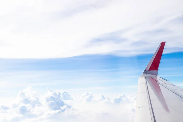 Plane wings in the sky with fluffy white clouds nature background