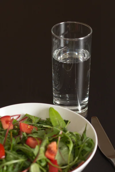 Un verre d'eau avec une salade de tomates légère — Photo