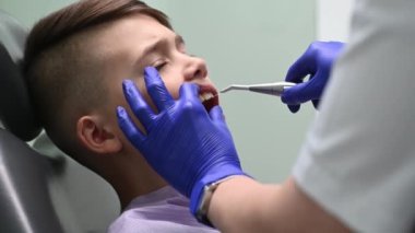 Diş hekimi dişlerini fırçalama prosedüründen sonra çocuğun dişlerini yıkar.