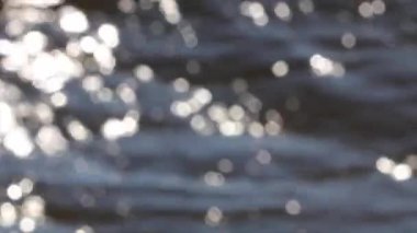 Su yüzeyindeki ışık yansıması, arka plandaki yumuşak ışığı yok etti. Bokeh güneşi su yüzeyine yansıyor. Güneş ışınları su akıntısında titreşiyor..