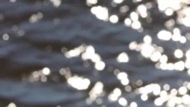 Su yüzeyindeki ışık yansıması, arka plandaki yumuşak ışığı yok etti. Bokeh güneşi su yüzeyine yansıyor. Güneş ışınları su akıntısında titreşiyor..