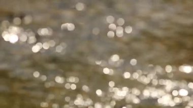 Su yüzeyindeki ışık yansıması, arka plandaki yumuşak ışığı yok etti. Bokeh güneşi su yüzeyine yansıyor. Güneş ışınları su akıntısında titreşiyor..