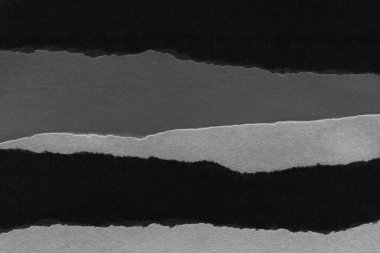 black and white dark Torn paper collage close-up. Texture made from various paper and cardboard parts. Damaged old paper background. Old grunge ripped torn vintage collage backdrop and background.