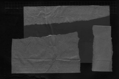 black and white dark Torn paper collage close-up. Texture made from various paper and cardboard parts. Damaged old paper background. Old grunge ripped torn vintage collage backdrop and background.