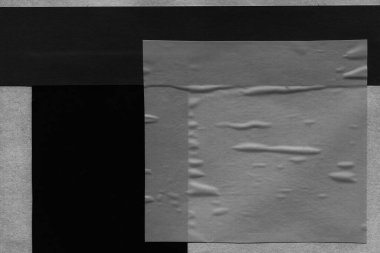 black and white dark Torn paper collage close-up. Texture made from various paper and cardboard parts. Damaged old paper background. Old grunge ripped torn vintage collage backdrop and background.