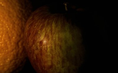 siyah arkaplan ve organik, portakallı taze elma