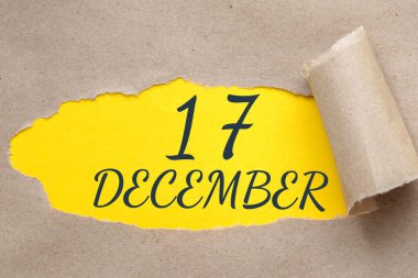 17 Aralık. Ayın 17. günü, takvim tarihi. Kenarları yırtılmış kağıt delikleri. Sarı arkaplan yırtık pırtık delikten görülebilir. Kış ayı, yılın günü konsepti..