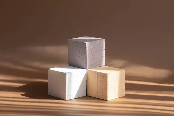 3D podyum, paketleme, kozmetik sunumları için. Üç farklı renk kübü, bej, beyaz, kahverengi, güneş ışığı ışınları şeklinde kaide şeklinde dizilmiş..