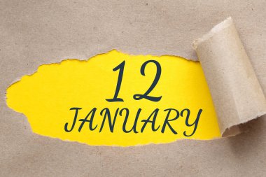 12 Ocak. Ayın 12. günü, takvim tarihi. Kenarları yırtılmış kağıt delikleri. Sarı arkaplan yırtık pırtık delikten görülebilir. Kış ayı, yılın günü konsepti..