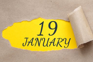 19 Ocak. Ayın 19. günü, takvim tarihi. Kenarları yırtılmış kağıt delikleri. Sarı arkaplan yırtık pırtık delikten görülebilir. Kış ayı, yılın günü konsepti..