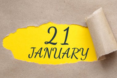 21 Ocak. Ayın 21inci günü, takvim tarihi. Kenarları yırtılmış kağıt delikleri. Sarı arkaplan yırtık pırtık delikten görülebilir. Kış ayı, yılın günü konsepti..