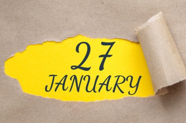 27 Ocak. Ayın 27. günü, takvim tarihi. Kenarları yırtılmış kağıt delikleri. Sarı arkaplan yırtık pırtık delikten görülebilir. Kış ayı, yılın günü konsepti..