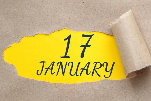 17 Ocak. Ayın 17. günü, takvim tarihi. Kenarları yırtılmış kağıt delikleri. Sarı arkaplan yırtık pırtık delikten görülebilir. Kış ayı, yılın günü konsepti..