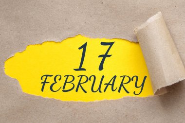 17 Şubat. Ayın 17. günü, takvim tarihi. Kenarları yırtılmış kağıt delikleri. Sarı arkaplan yırtık pırtık delikten görülebilir. Kış ayı, yılın günü konsepti..