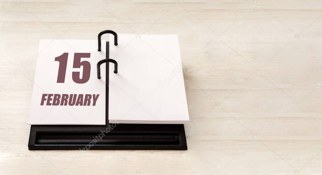 february 15. 15th day of month, calendar date.  Stand for desktop calendar on beige wooden background. Concept of day of year, time planner, winter month.