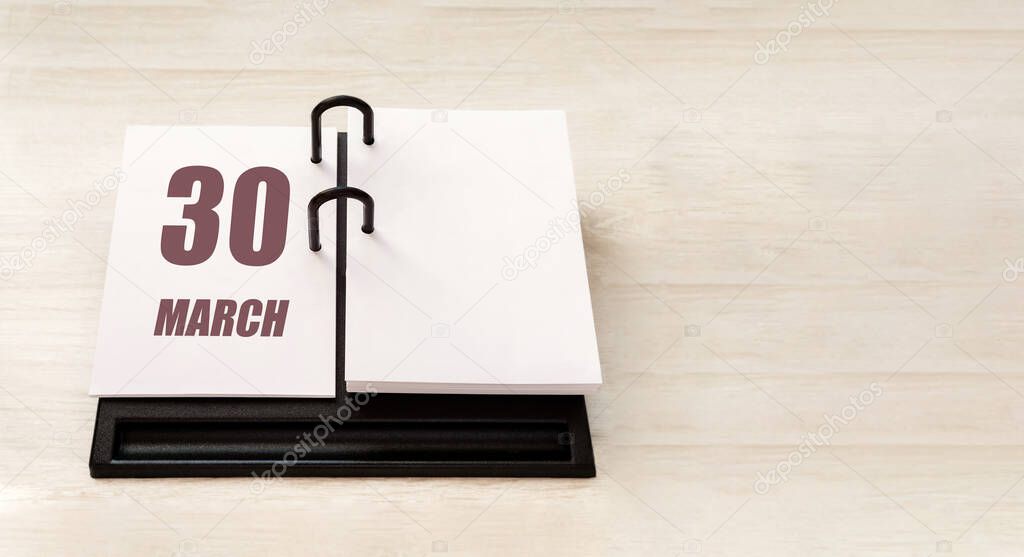 march 30. 30th day of month, calendar date. Stand for desktop calendar on beige wooden background. Concept of day of year, time planner, spring month.