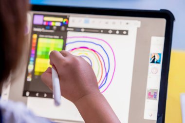 Küçük kız dijital kalem kullanıyor ve tablete çizim yapıyor yaratıcı olmak ve evde dijital sanat ve öğrenim yapmak için ekranlara dokunuyor.