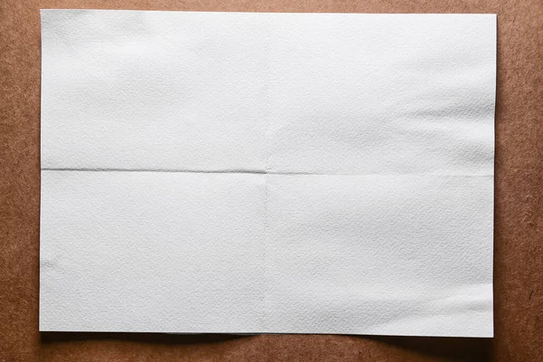 white empty paper folded sheet of paper on a brown background
