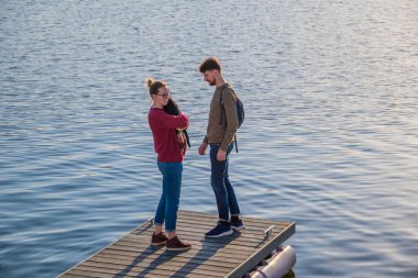 Kazan, Rusya - 14 Ekim 2020: Gündelik giysiler içinde güzel bir çift, bir erkek ve bir kız rıhtımın kenarında birbirlerine bakıyorlar. Kız kucağında küçük bir köpek tutuyor..