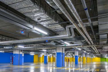 Ticari bir binanın yeraltı otoparkında. Havalandırma ve havalandırma sisteminin havalandırma kanalları, yangın söndürme sisteminin boruları, tavanın altındaki elektrik kabloları..