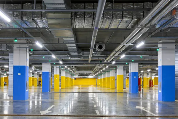 Underground parking of a commercial building with navigation system sensors. Air conditioning and ventilation ducts, fire extinguishing system pipes, electric cable channels under the ceiling.