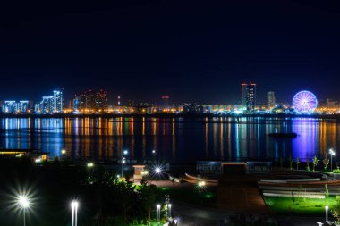 Nehir kıyısındaki yanan binalar ve fenerler, gece şehrinin çok renkli ışıkları suya yansıdı..
