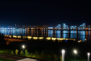 Nehir kıyısındaki yanan binalar ve fenerler, gece şehrinin çok renkli ışıkları suya yansıdı..