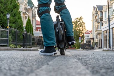 Sürücünün bacakları elektrikli bir tek tekerlekli bisiklette (EUC) koruyucu dişli. Elektrikli bir tekerle şehirde dolaşıyorum..