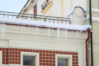 Binanın çatısı karla kaplı, buz sarkıtları tehlikeli bir şekilde asılı ve alçıdan dökülüyor..