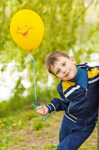 Lächelnder glücklicher Junge mit gelbem Luftballon — Stockfoto