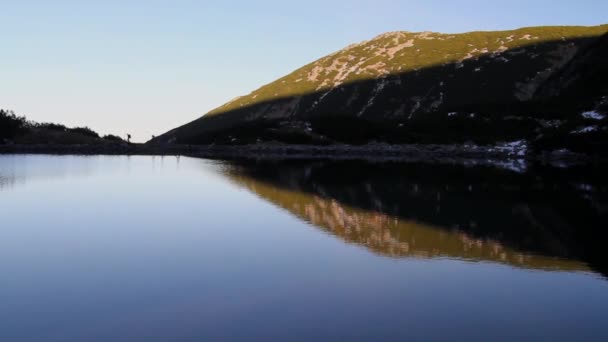 Senderistas pasando por el horizonte sobre el lago — Vídeos de Stock