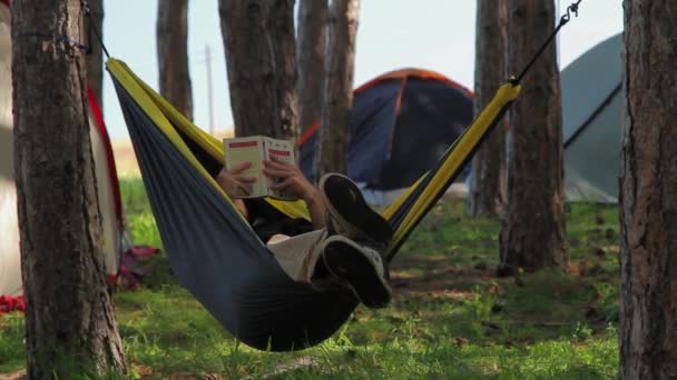 Teenager reading a book in a hammock — Stock Video