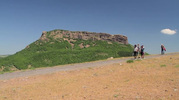 Grupp turister passerar genom enorma rock — Stockvideo