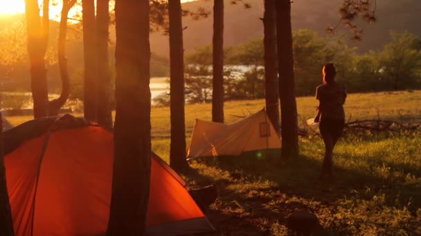 Pige nyder solnedgangen nær telt – Stock-video