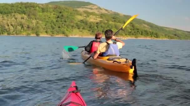 Casal de canoagem em um lago, seguido de segundo barco — Vídeo de Stock