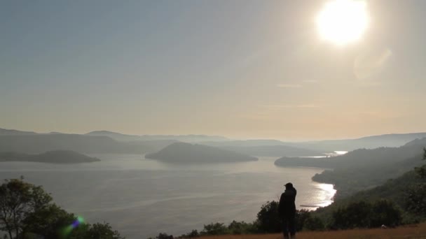 Mulher assistindo o pôr do sol sobre um lago gigante com ilhas — Vídeo de Stock