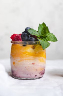 Mangolu yoğurt ve yabanmersinli böğürtlen reçeli, ahududu ve bardakta nane yaprağı.