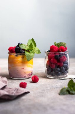 Mangolu yoğurt ve yabanmersinli böğürtlen reçeli, ahududu ve bardakta nane yaprağı.