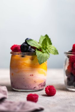 Mangolu yoğurt ve yabanmersinli böğürtlen reçeli, ahududu ve bardakta nane yaprağı.