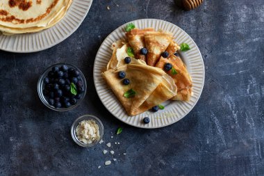 Ballı krepler, nane yaprakları, gri taşlı yaban mersinleri. Kopyalama alanı ile kapatın. Lezzetli krepler, ince krepler.