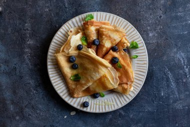 Ballı krepler, nane yaprakları, gri taşlı yaban mersinleri. Kopyalama alanı ile kapatın. Lezzetli krepler, ince krepler.
