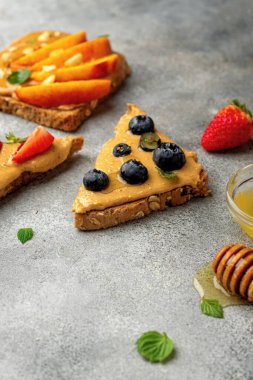Tam tahıllı tost seti, fıstık ezmesi, bal, nane, fıstık, nektarin, yabanmersini ve çilek. sağlıklı kahvaltı konsepti