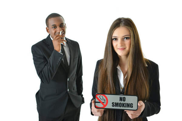 Business woman holding no smoking sign and businessman smoking a cigarette