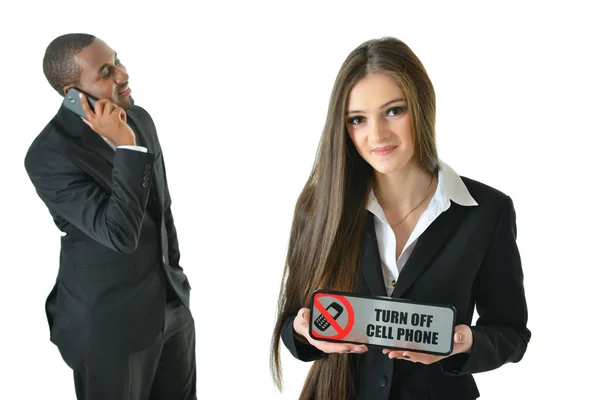 Mujer de negocios sosteniendo Apague el cartel del teléfono celular con expresión sonriente y un hombre de negocios hablando por teléfono — Foto de Stock