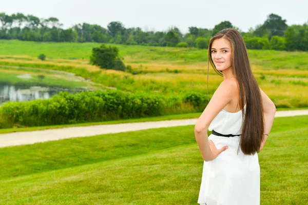 Glad och frisk flicka stående framför naturliga scen — Stockfoto