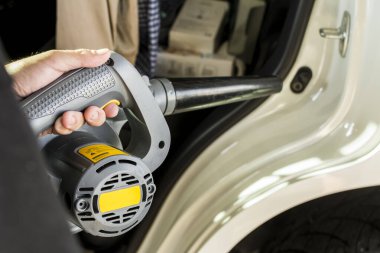 Araba kapısının pervazını kurutmak için profesyonel bir hava üfleyicisi kullanıyor ve dış kapağı C sütunun altına kapatıyor. Otomatik temizleme servisinin bir parçası.