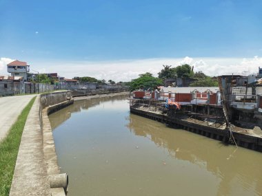 Metro Manila 'da Las Pinas ve Cavite' de Bacoor sınırında bulunan Zapote Nehri. Nehir kıyısında bir cadde akıyor..